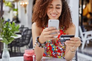 frau-mit-happy-look-hält-moderne-kreditkarte-macht-online-shopping-via-smartphone